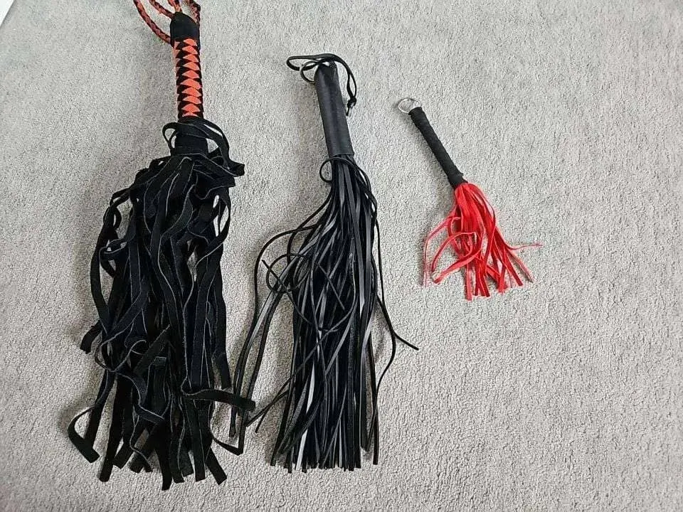Three flogger-style tools on a carpet, used here for a kink dating alternatives hub