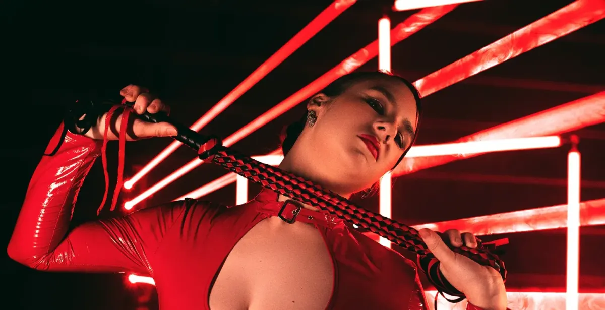 Person in a red latex outfit holding a braided cord for a guide to kink dating apps Person in a red latex outfit holding a braided cord for a guide to kink dating apps