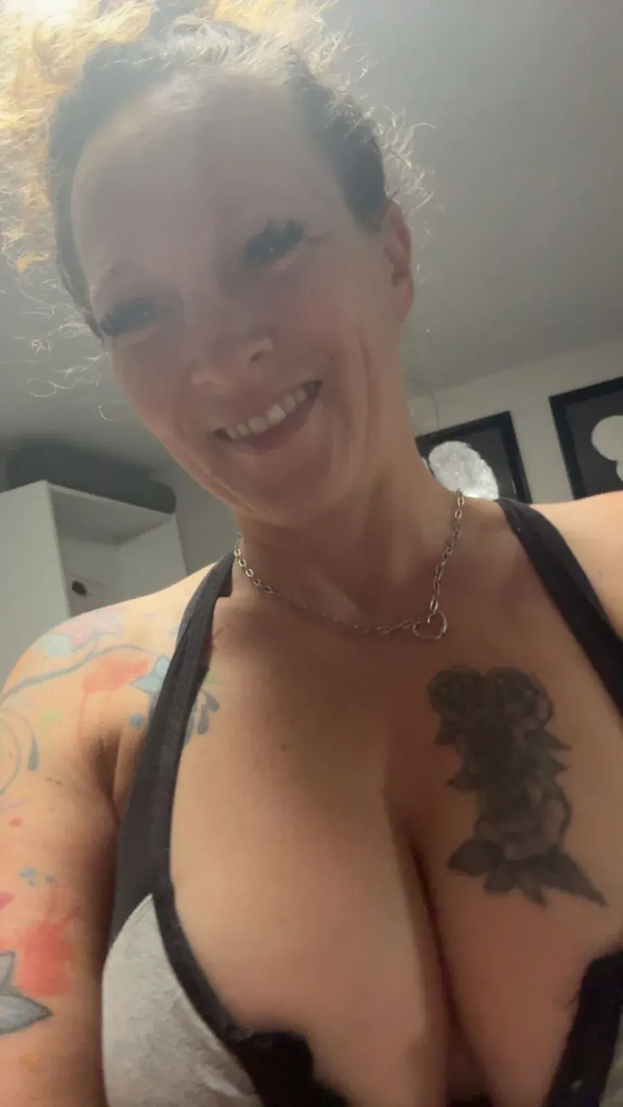 Smiling woman with tattoos and a heart necklace for a privacy-focused adult dating guide