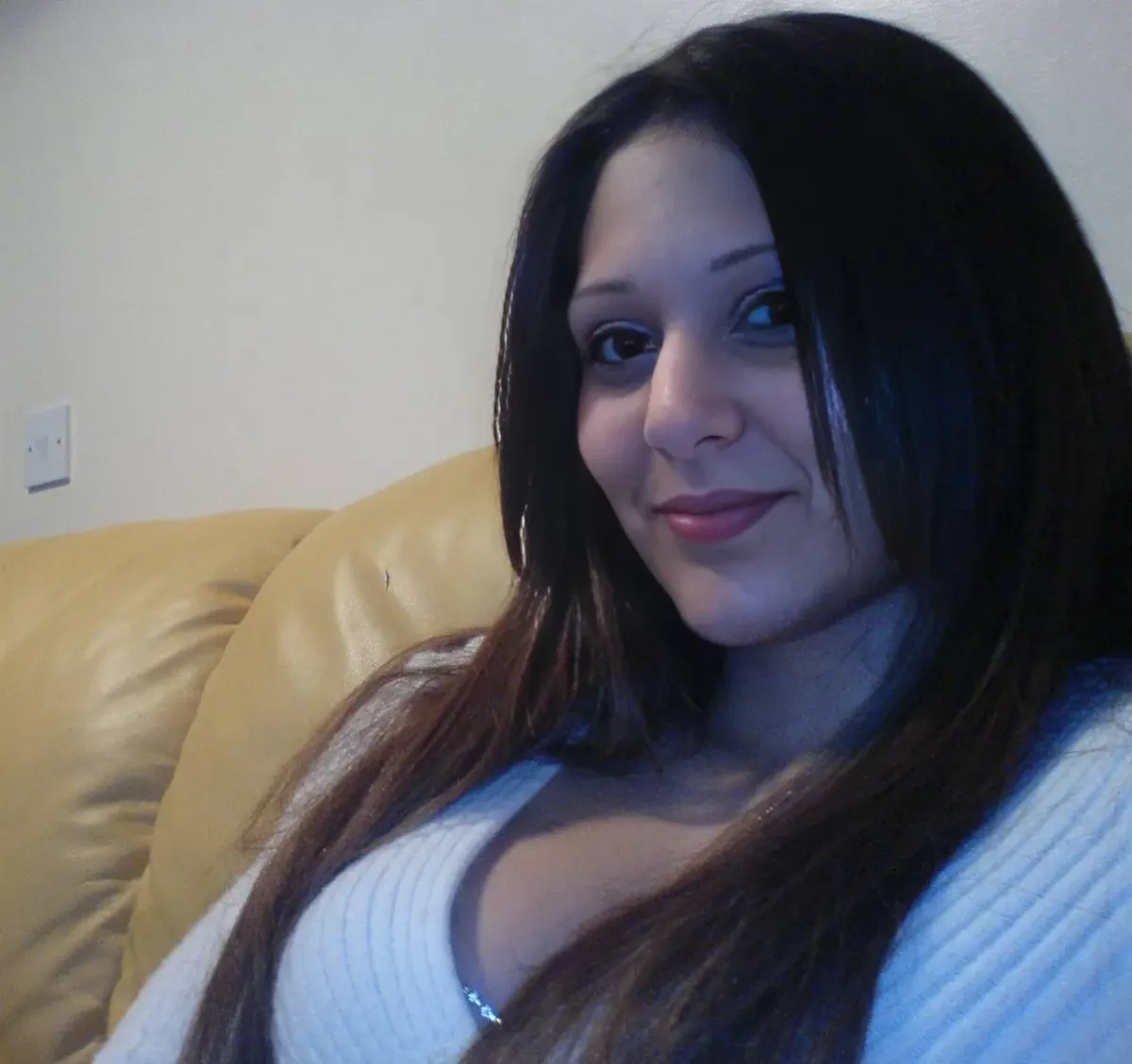 Adult woman in a white knit sweater seated on a tan couch for a privacy-focused dating comparison Adult woman in a white knit sweater seated on a tan couch for a privacy-focused dating comparison
